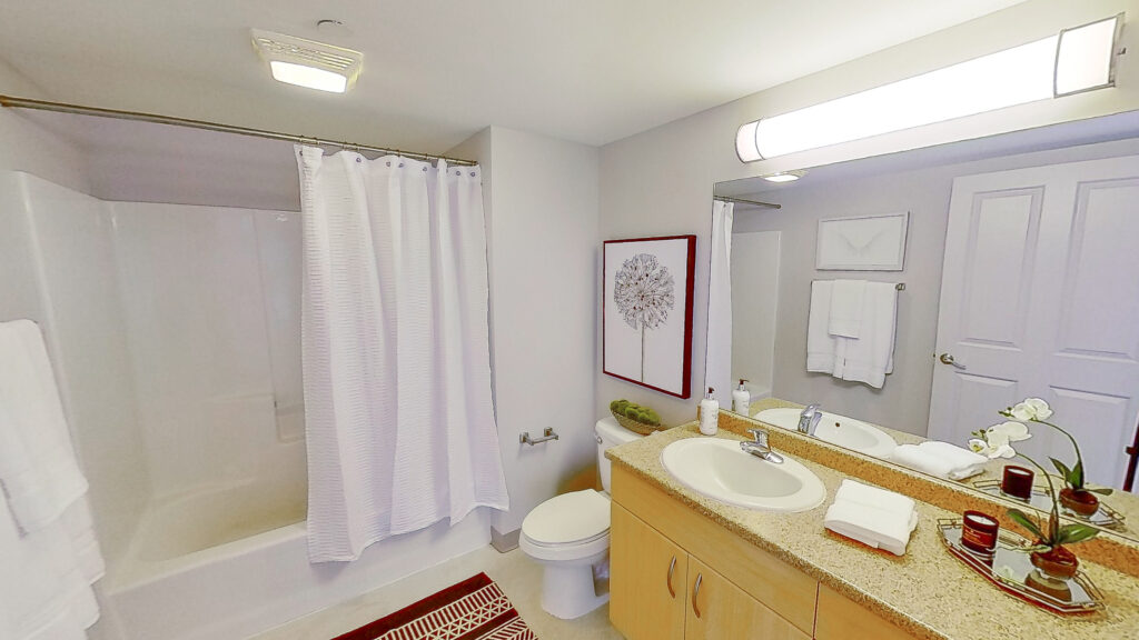 A bathroom with a toilet, sink and shower.